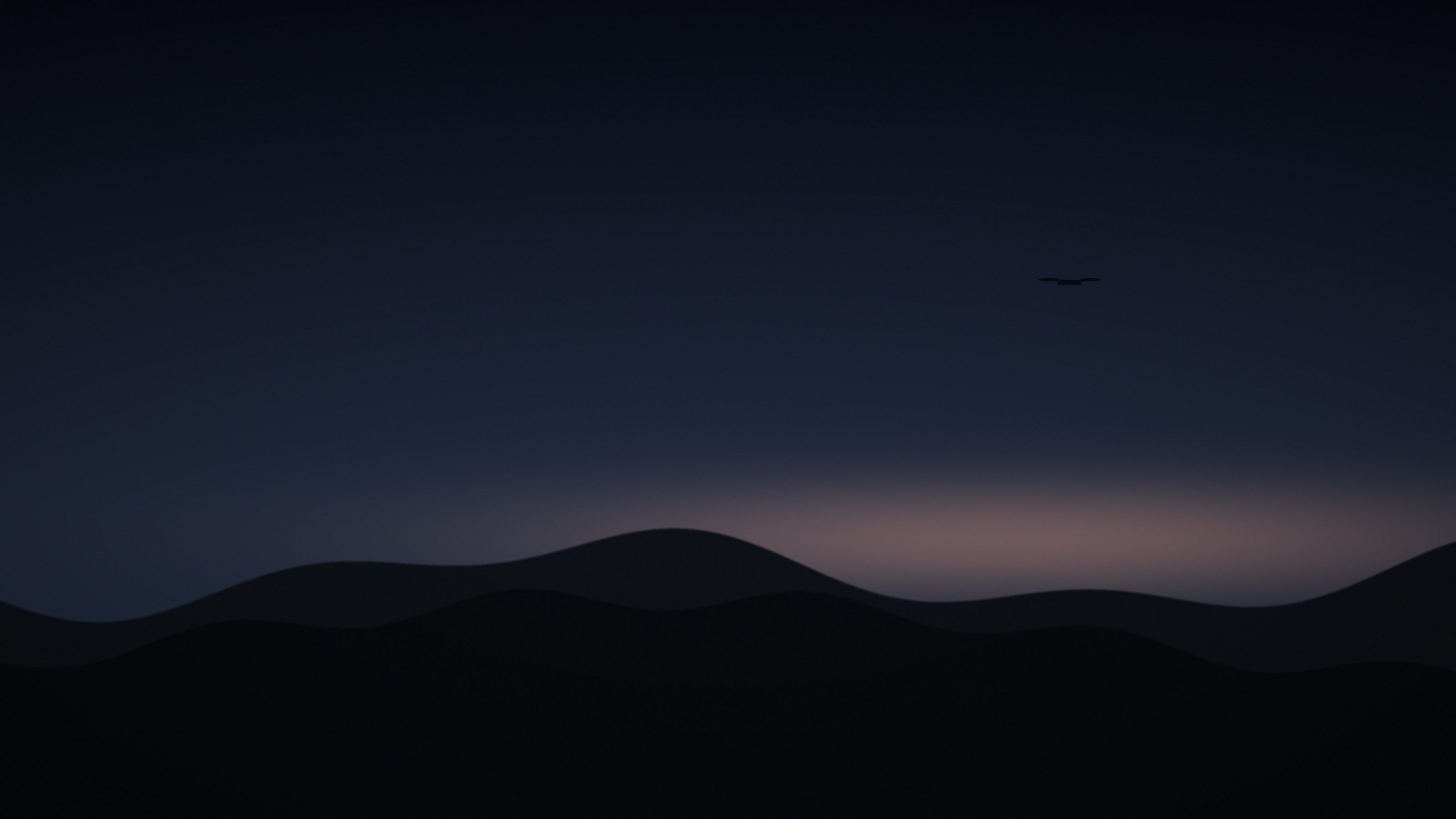 A drone against a dusk sky over hills